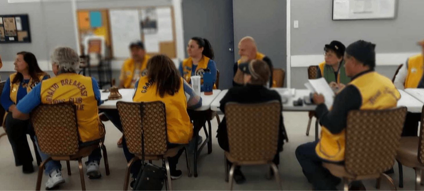 Lions members in gold vests sitting around tables at a club meeting.